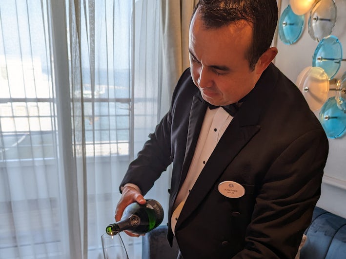 Jean, a butler on Crystal Serenity, pours Champagne. (Photo: Colleen McDaniel)