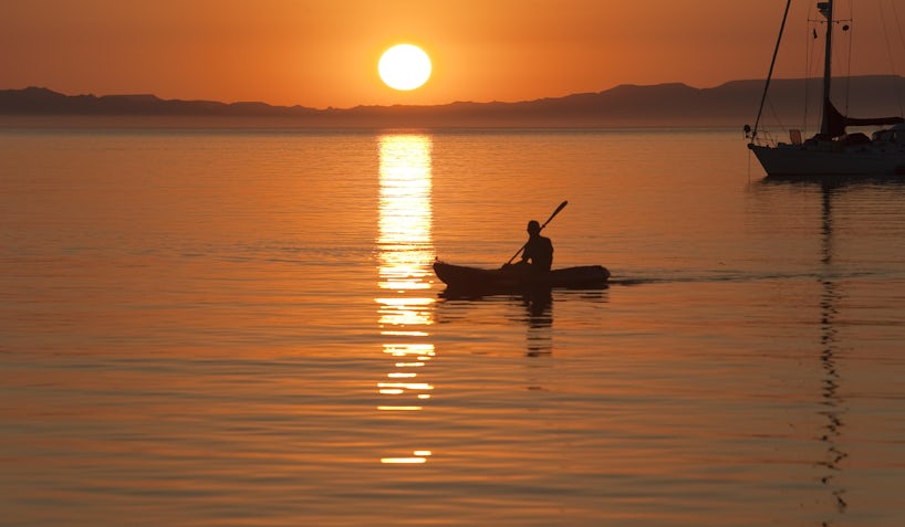 Photograph of a kayaker in the Sea of Cortez with the sun setting in the background - Photography by Stephen N Haynes via Shutterstock