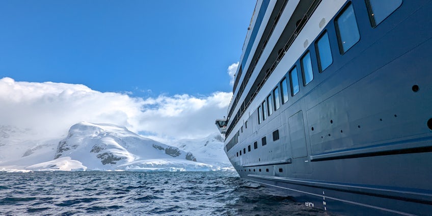 A cruise ship sits in Antarctica, pointed toward a glacier. (Photo: John Roberts)