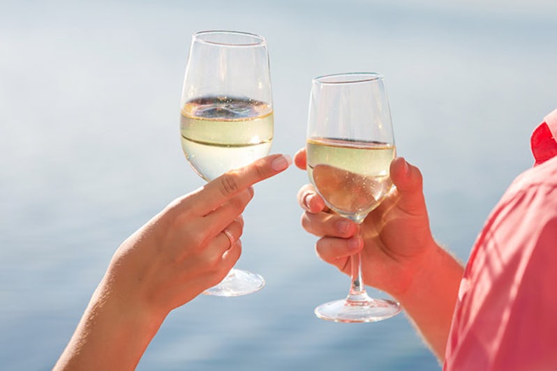 Cruisers raise their glasses of white wine in celebration.  (Photo: illustrissima/Shutterstock)