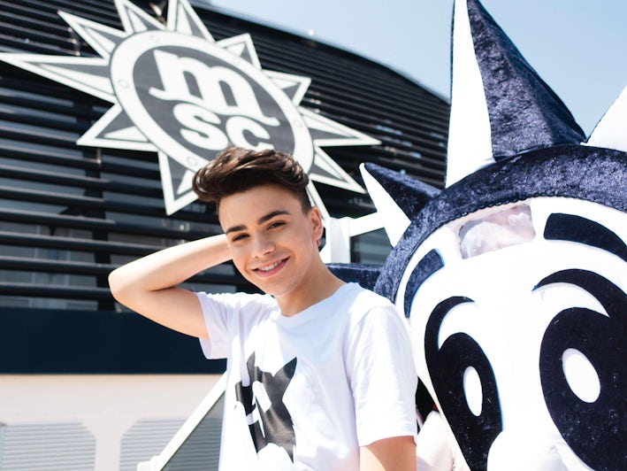 Teenage boy posing in front of MSC Grandiosa funnel