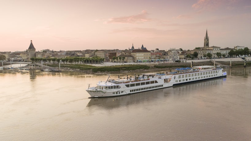 Exterior drone shot of S.S. Bon Voyage cruising along a river at sunset