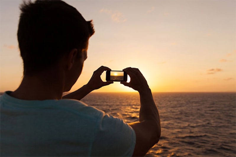 Man taking a picture of the sunset on a cruise