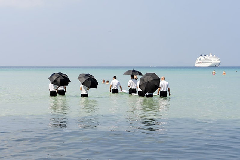 Seabourn officers with umbrellas pushing a cooler out to water