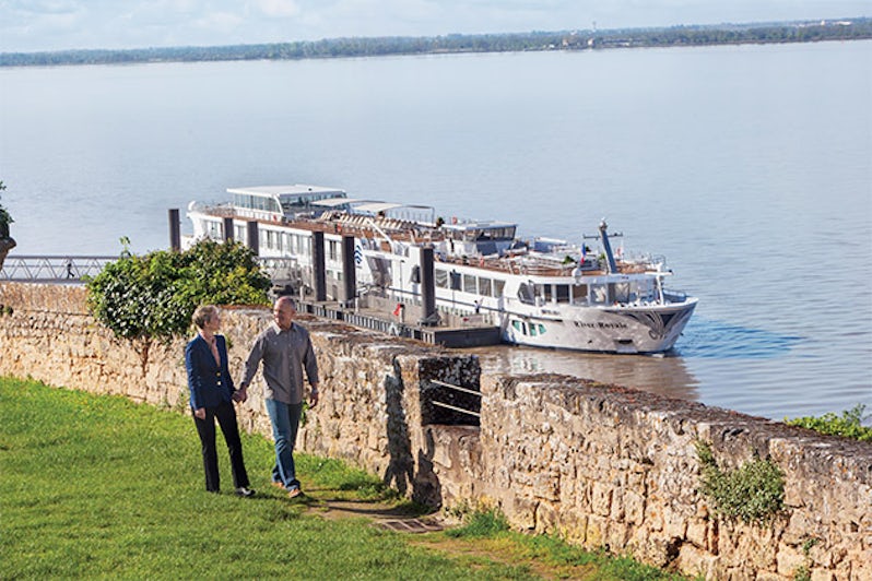Couple strolling in port with river ship docked in background