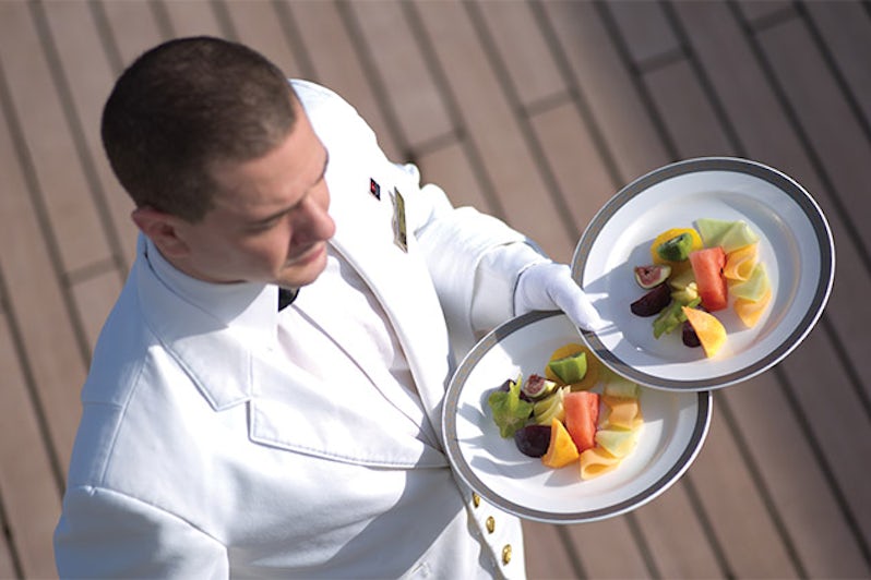 Luxury cruise waiter carrying two plates of fresh fruit