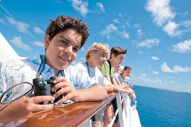 Kids looking out over a cruise deck railing on a Paul Gauguin ship