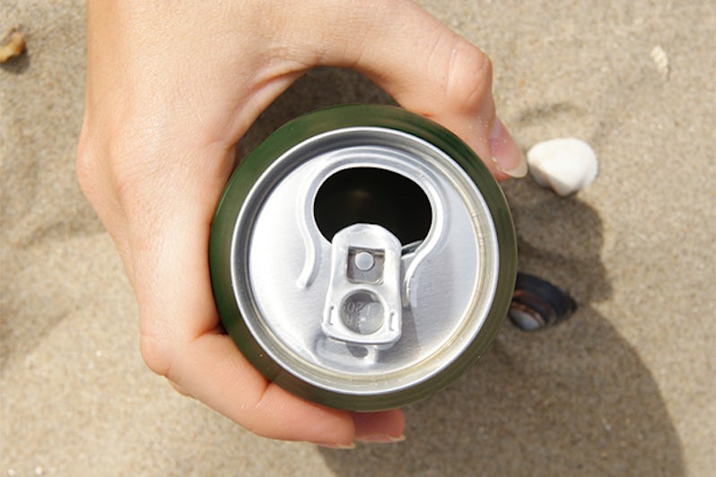 Can in hand on the beach