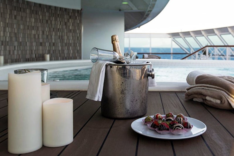 Bottle of Champagne, candles and chocolate-covered strawberries beside a hot tub