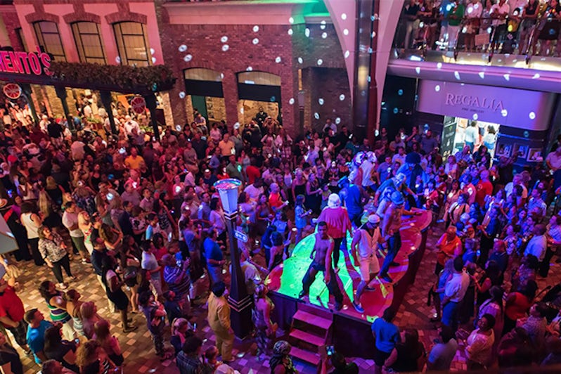 Large group of people dancing in the low-lit Royal Promenade on Oasis of the Seas