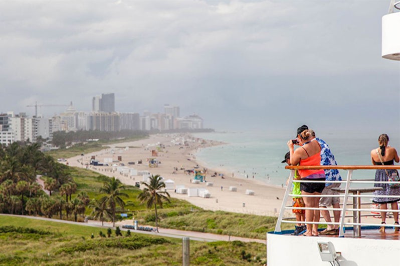 Passengers take photographs of a beach at Sailaway, while Carnival Sensation cruises out of Miami