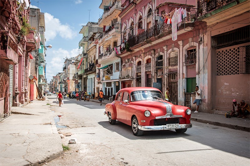 Classic red American car being used as a taxi in downtown Havana, Cuba, with locals