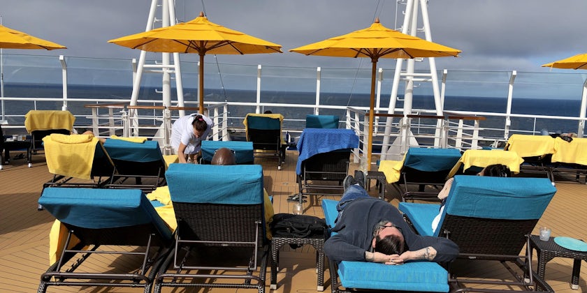 People laying in loungers under umbrellas at Serenity on Carnival Panorama