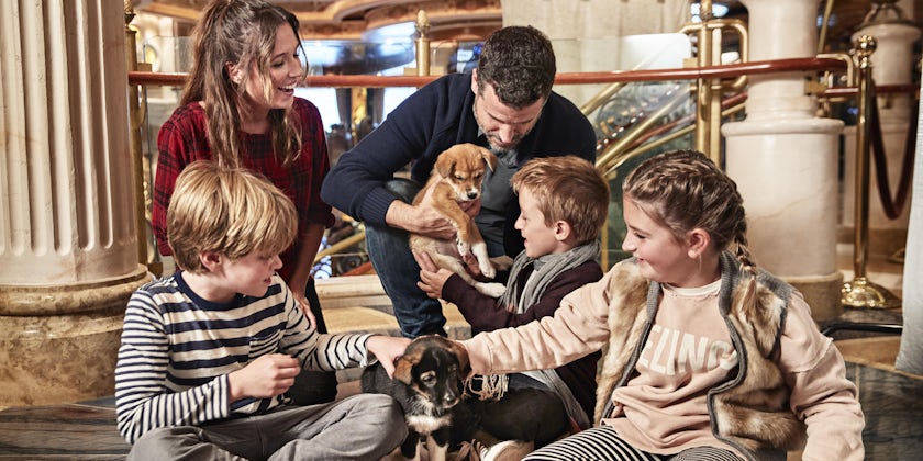 Family on a Princess cruise playing with a dog hosted by Princess' "Puppies in the Piazza" program (Photo: Princess Cruises)