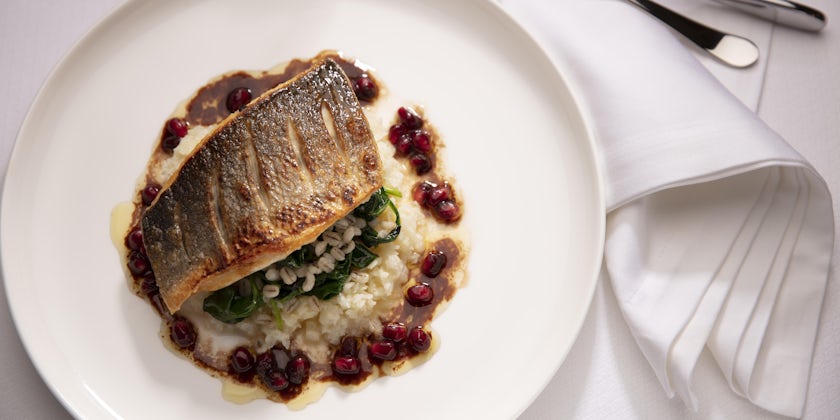 Close-up shot of a plated grilled branzino dish with cauliflower rice, barley, spinach and pomegranate