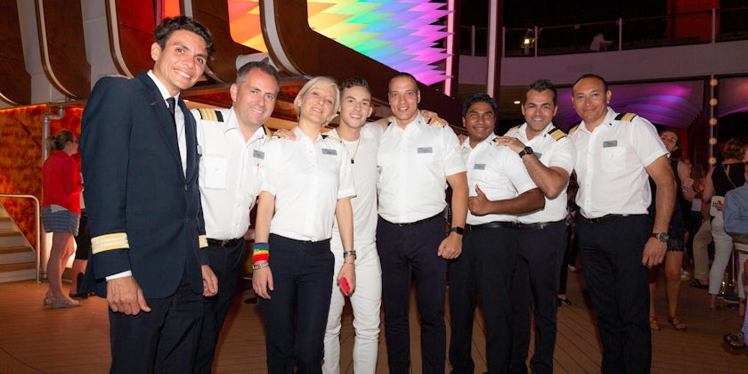 Celebrity crew and officers posing for a photo on the pool deck during Pride Party at Sea on Celebrity Edge