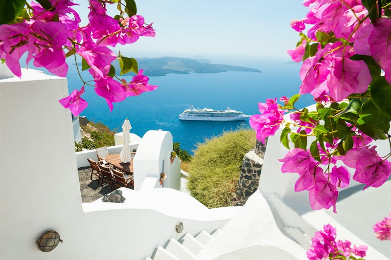 Cruise ship sailing past Santorini, from the view of white buildings and pink spring flowers