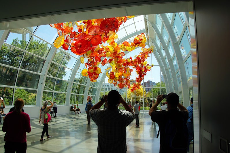 Tourists admiring the hanging glass flowers in Chihuly Garden and Glass Museum's conservatory