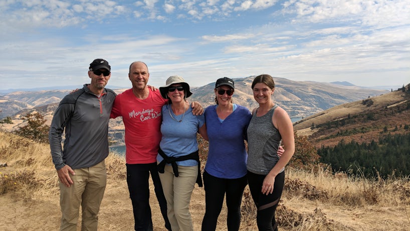 Hikers pose at the top of a climb with mountains in the background. (Photo: John Roberts)
