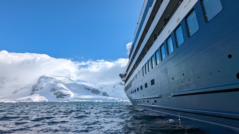 A cruise ship sits in Antarctica, pointed toward a glacier. (Photo: John Roberts)