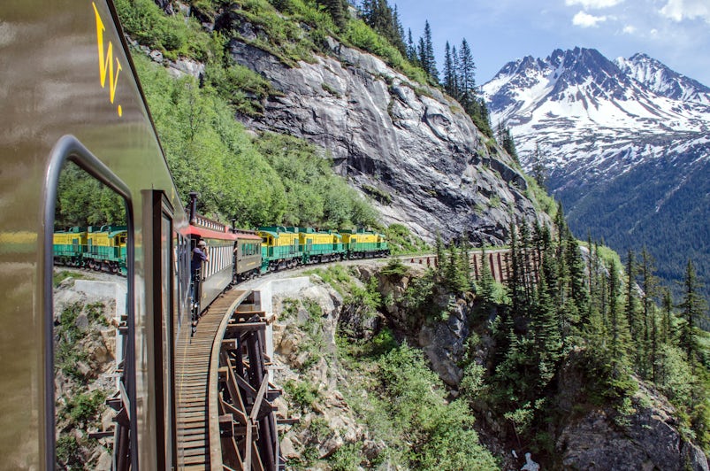 Exterior shot of White Pass and Yukon Railroad train bending around a mountain in Alaska