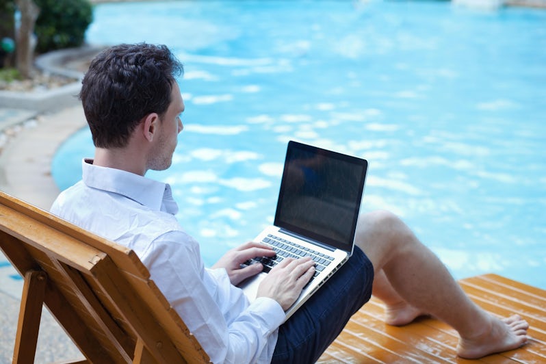 business man with laptop in luxury hotel near swimming pool
