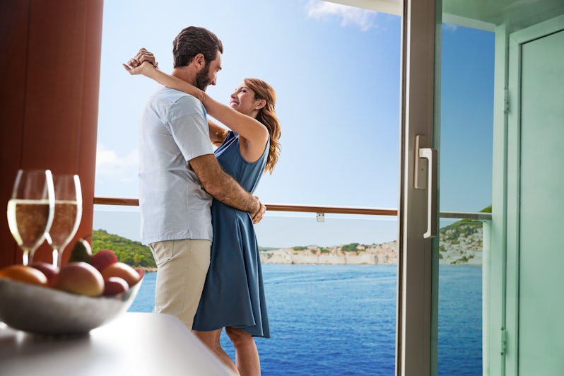 A couple in a balcony cabin on an NCL ship with Dubrovnik in the background