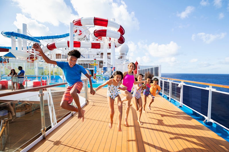 Six kids of all ages holding hands and jumping on the Carnival Horizon pool deck