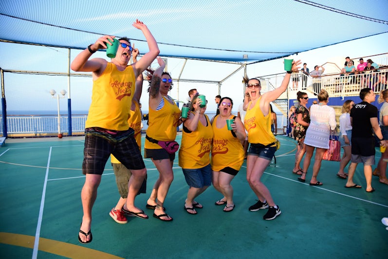 Flip cup tournament team jumping and smiling in matching shirts on Impractical Jokers Cruise 4