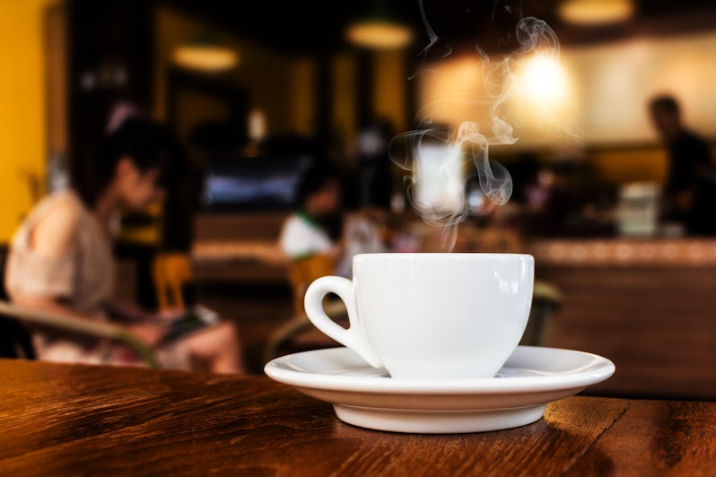 Close-up shot of a cup of steaming coffee on the table in a cafe