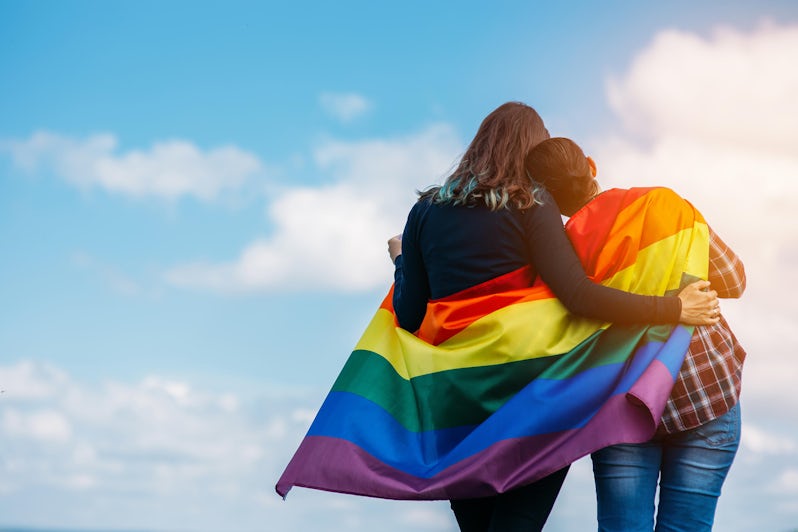Couple wrapping the Pride Flag around them in spirit of the LGBT community (Photo: Angyalosi Beata/Shutterstock)