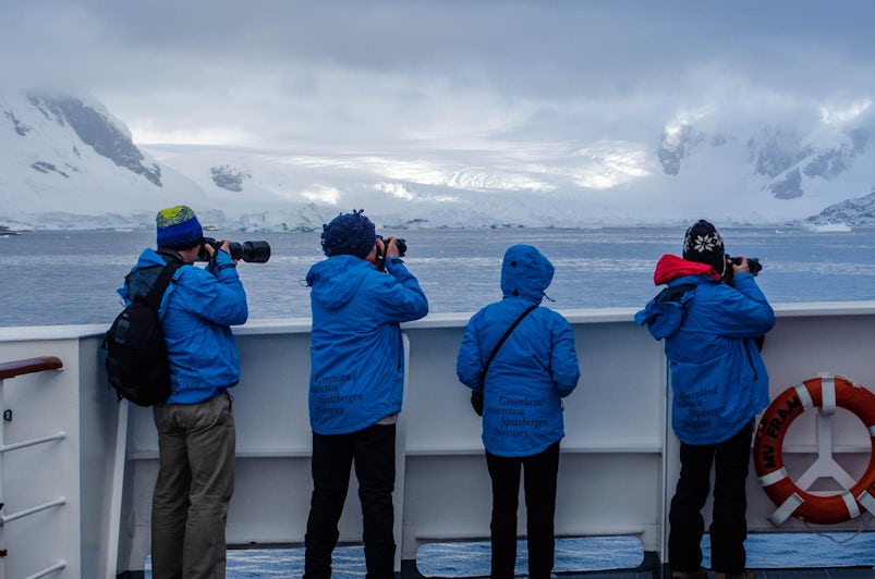 Photo of four passengers bundled up and shooting photographs from the exterior deck of Hurtigruten's Fram in Antarctica 