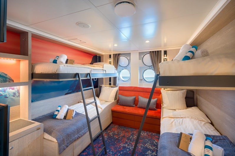 Shot of a blue, white and orange porthole cabin with bunk beds on Janssonius