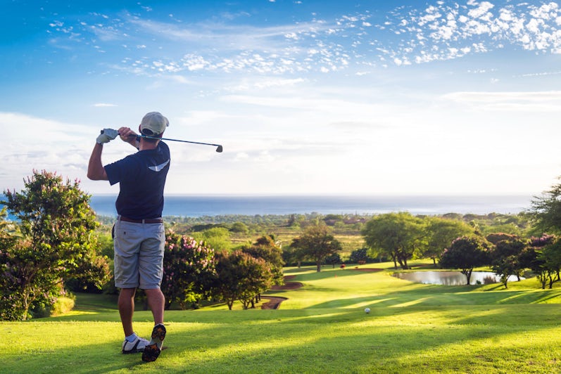 Man golfing on open field with the ocean in distance (Photo: Allen.G/Shutterstock)