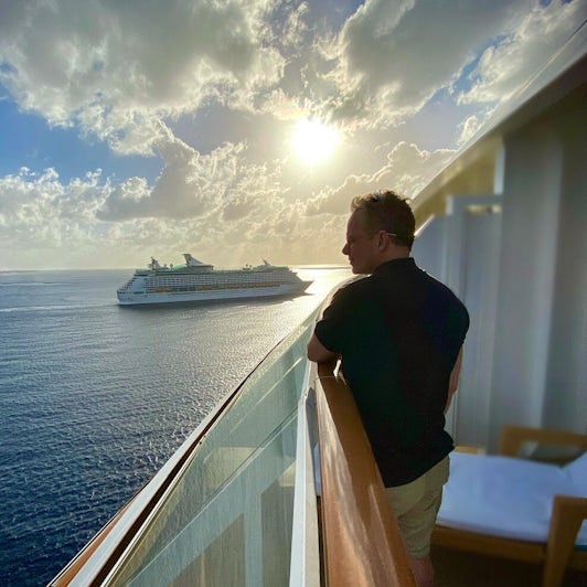 Male passenger looking out towards sea from the Haven Owner's Suite balcony on Norwegian Escape 