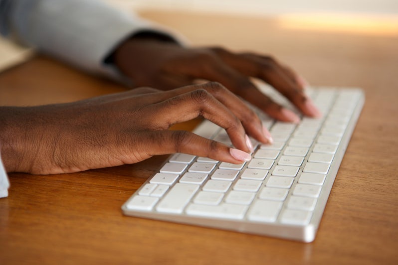 Close-up shot of black woman typing on a computer keyboard