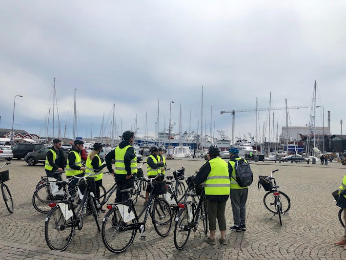 Group of bicyclists dressed in helmets and bright yellow jackets on a shore excursion in Skagen