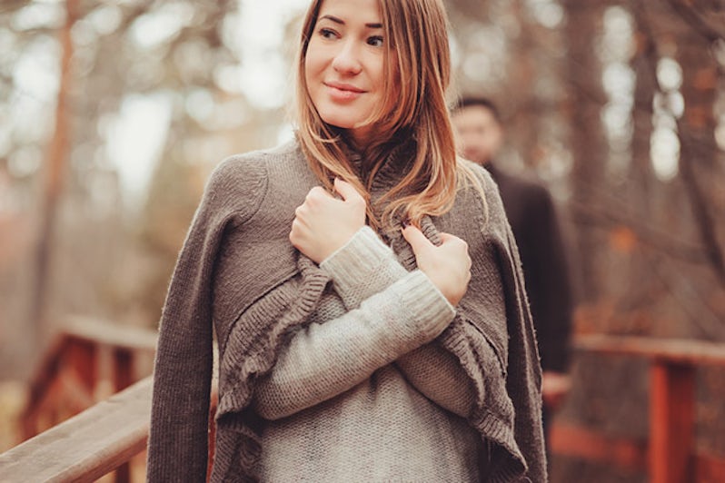 Woman in cozy warm cardigan walking outdoor in autumn forest
