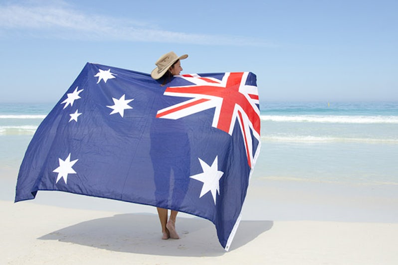 woman wearing akubra hat and with Australian flag around shoulder standing at tropical Australian beach