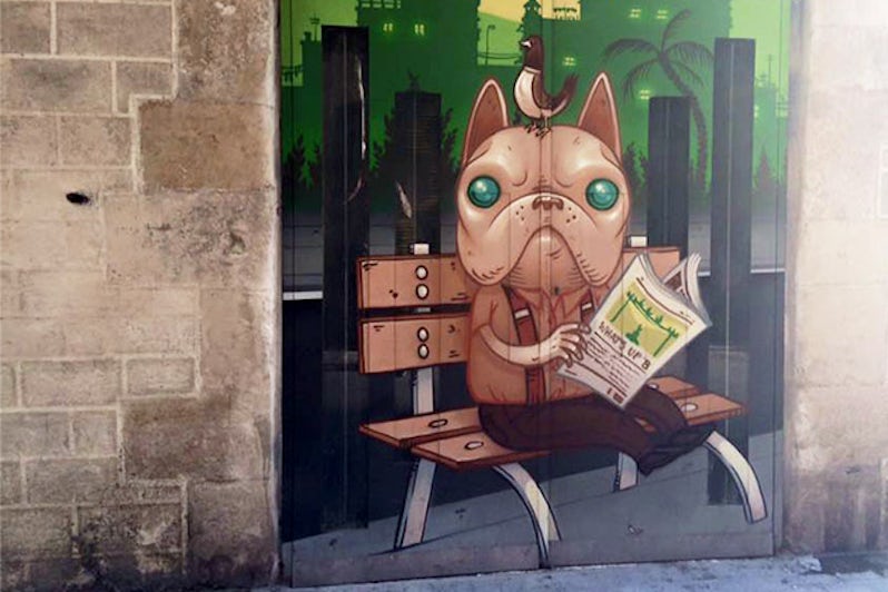 Graffiti of a cartoon dog reading the paper on a park bench