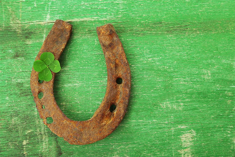 Horseshoe and four leaf clover on green tabletop