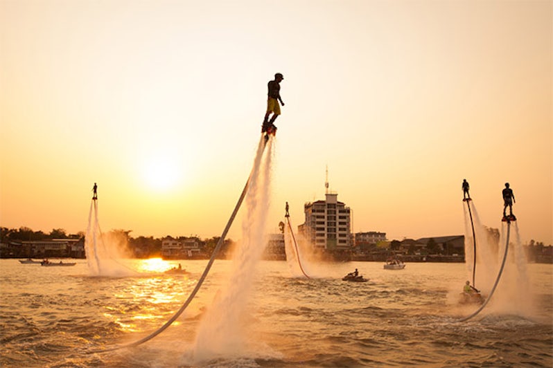 Silhouettes of flyboarders at sunset