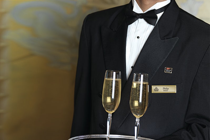 Cunard butler in tuxedo serving two glasses of Champagne on a platter