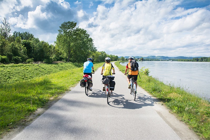 People riding bicycles on a cycle path near Danube River in Austria on a sunny day