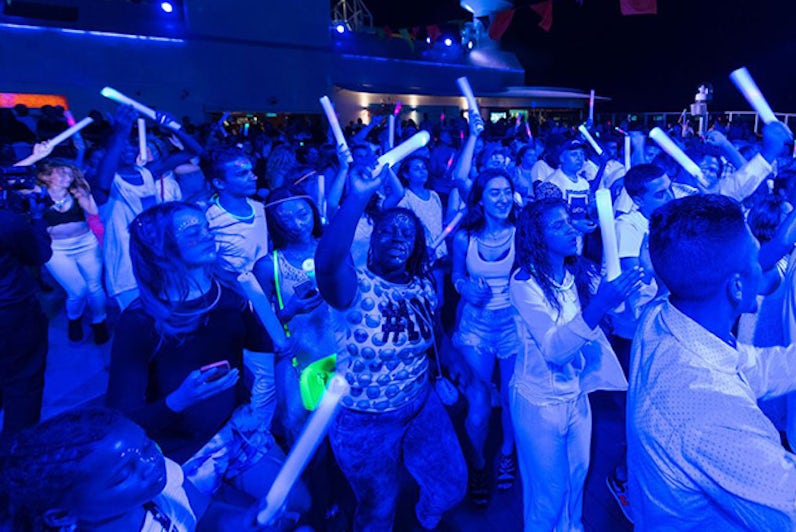 Group of young below dancing under blacklights at the Glow Party on Norwegian Breakaway