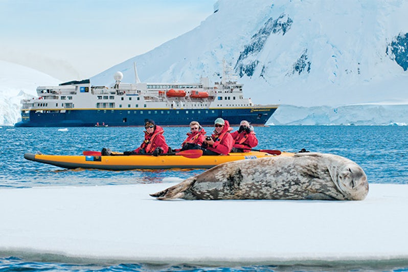 Lindblad Expeditions passengers kayaking past a seal in Antarctica