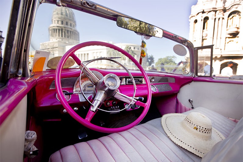 Interior of a hot pink American car in Havana, Cuba with Capitol building in the background 