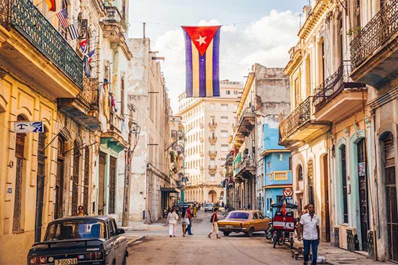 A cuban flag with holes waves over a street in Central Havana