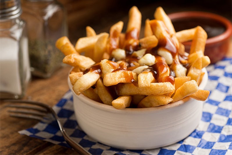 Close-up shot of Poutine in a bowl on a blue checkered tablecloth