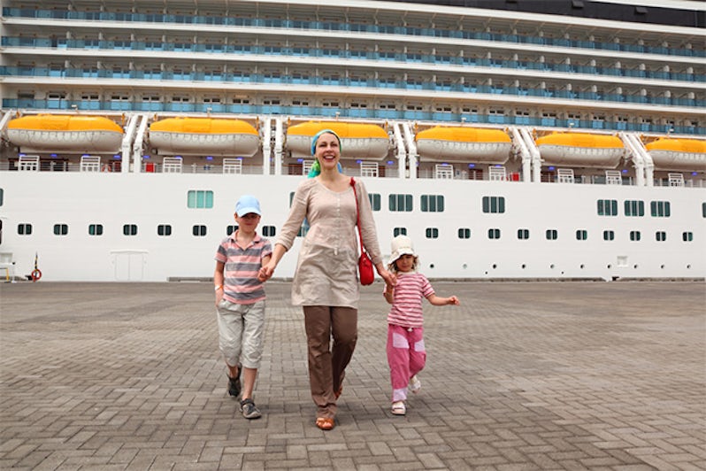 mother, daughter and son walking in dock and holding for hands, big cruise ship on background